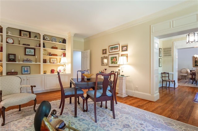 dining room featuring hardwood / wood-style flooring, ornamental molding, and an inviting chandelier