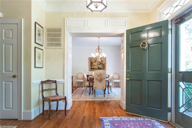 entryway featuring an inviting chandelier, ornamental molding, and hardwood / wood-style flooring