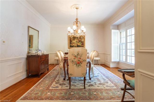 dining area featuring wood-type flooring, ornamental molding, and a chandelier