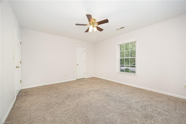 empty room with visible vents, carpet flooring, baseboards, and ceiling fan