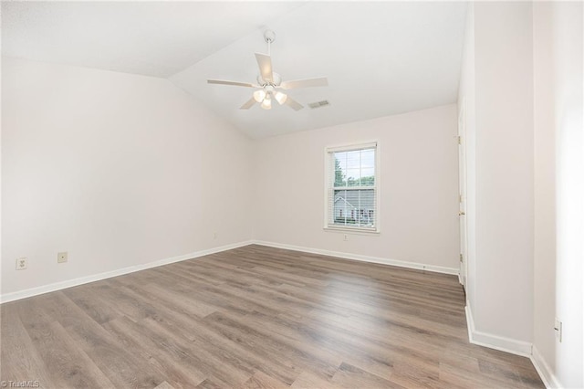 empty room with a ceiling fan, visible vents, wood finished floors, baseboards, and lofted ceiling