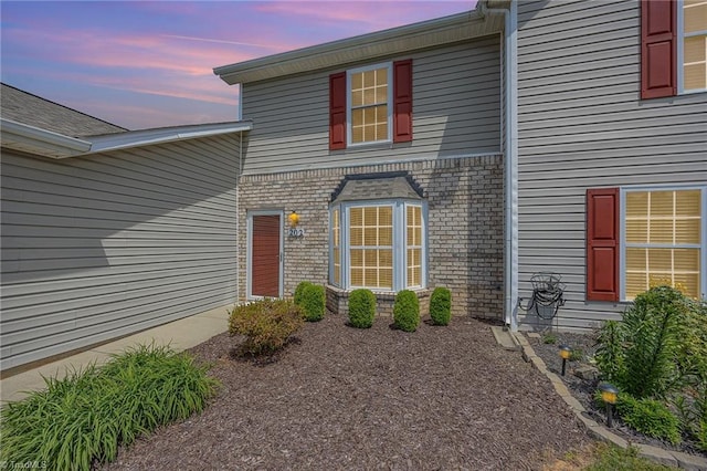 exterior entry at dusk featuring brick siding