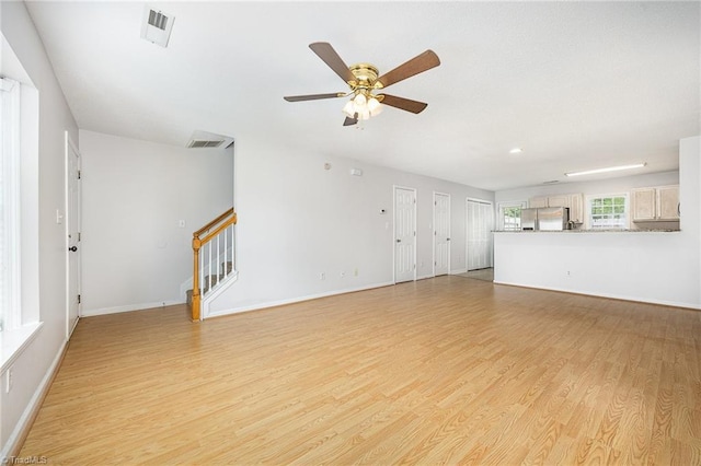 unfurnished living room featuring visible vents, a ceiling fan, stairs, and light wood finished floors