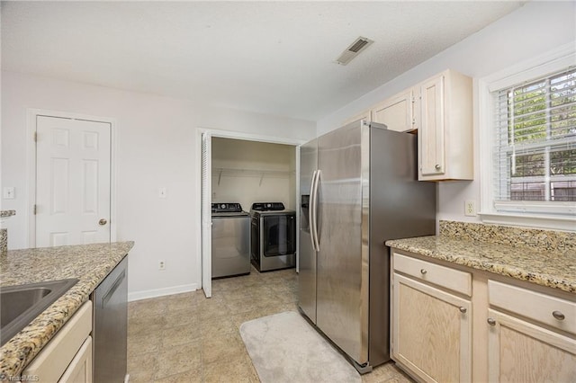kitchen featuring independent washer and dryer, visible vents, appliances with stainless steel finishes, baseboards, and light brown cabinets