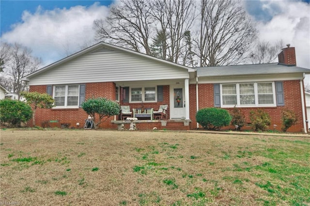 ranch-style home featuring covered porch and a front lawn