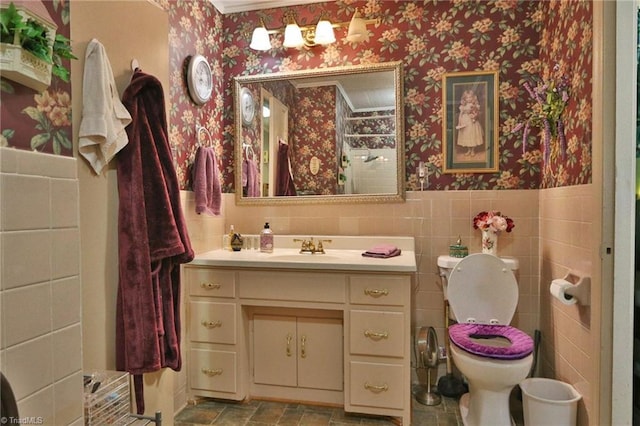 bathroom featuring crown molding, vanity, toilet, and tile walls