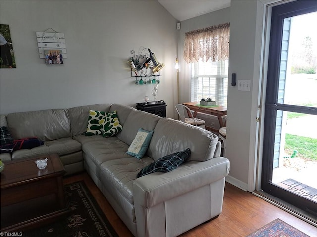 living room with light hardwood / wood-style flooring, a wealth of natural light, and vaulted ceiling