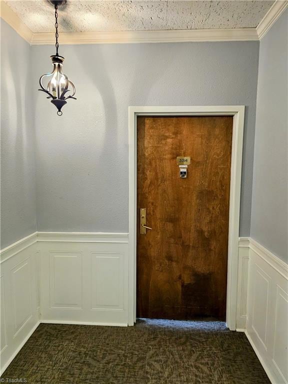 doorway to outside with crown molding, a textured ceiling, and dark carpet