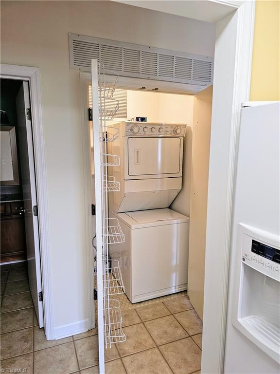 laundry room featuring stacked washer and dryer and light tile patterned floors