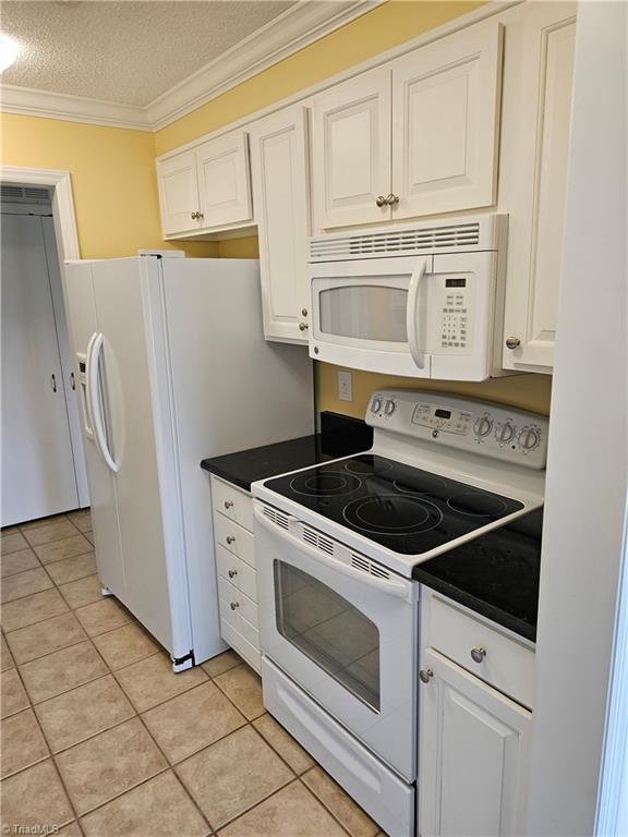 kitchen featuring ornamental molding, white cabinetry, light tile patterned flooring, a textured ceiling, and white appliances