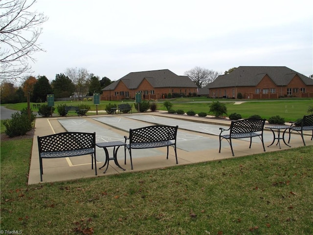 view of property's community featuring shuffleboard and a yard