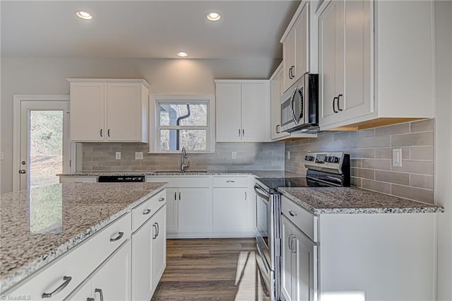 kitchen with stainless steel appliances, sink, white cabinetry, tasteful backsplash, and light stone countertops