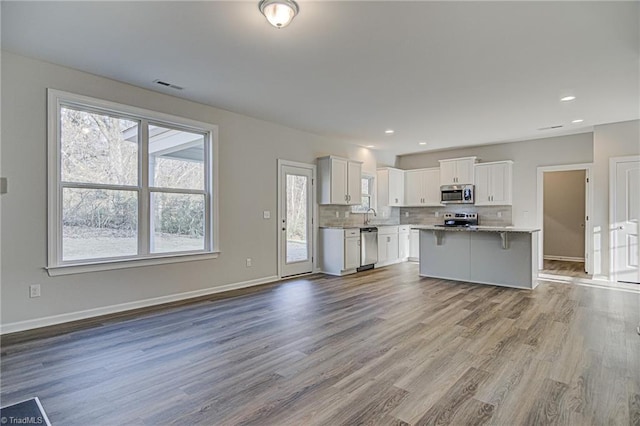 kitchen with stainless steel appliances, light wood-type flooring, white cabinets, and a center island