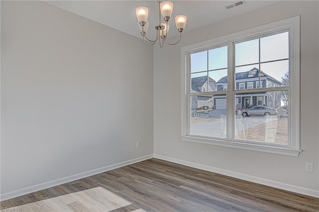 empty room with a chandelier and hardwood / wood-style flooring