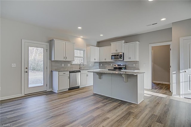 kitchen with sink, stainless steel appliances, white cabinetry, and a kitchen island