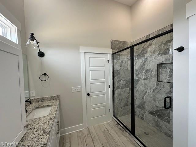 bathroom with hardwood / wood-style flooring, vanity, and a shower with shower door