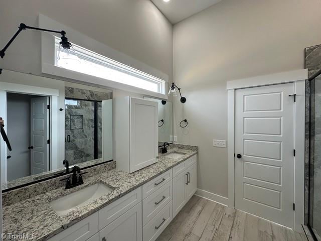 bathroom featuring hardwood / wood-style floors, vanity, an enclosed shower, and a towering ceiling