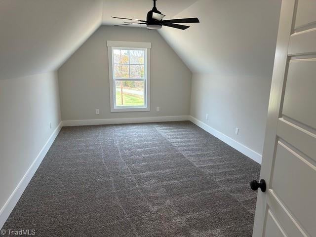 additional living space featuring vaulted ceiling, dark carpet, and ceiling fan