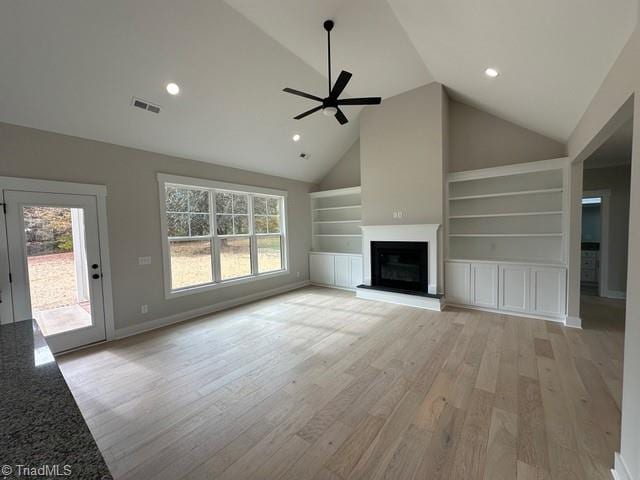 unfurnished living room with a wealth of natural light, high vaulted ceiling, and light hardwood / wood-style floors