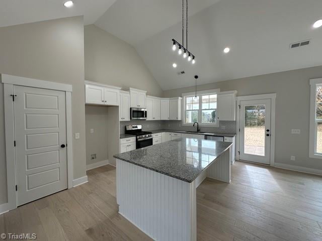 kitchen with white cabinets, a center island, stainless steel appliances, and light hardwood / wood-style flooring