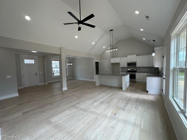 interior space featuring light wood-type flooring, stainless steel appliances, ceiling fan, white cabinets, and a center island