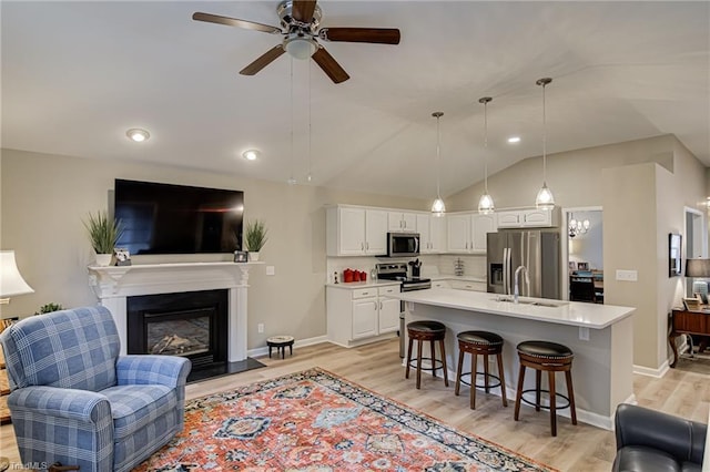 living room featuring sink, light wood-type flooring, ceiling fan, and lofted ceiling