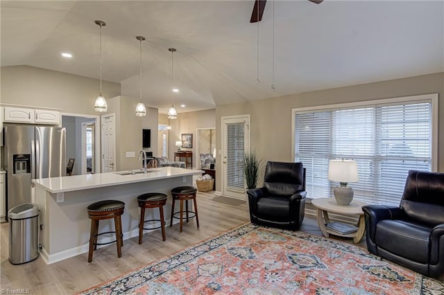 kitchen with pendant lighting, white cabinets, stainless steel refrigerator with ice dispenser, sink, and a kitchen breakfast bar