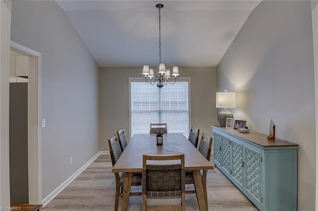 dining space with lofted ceiling, light hardwood / wood-style flooring, and a notable chandelier