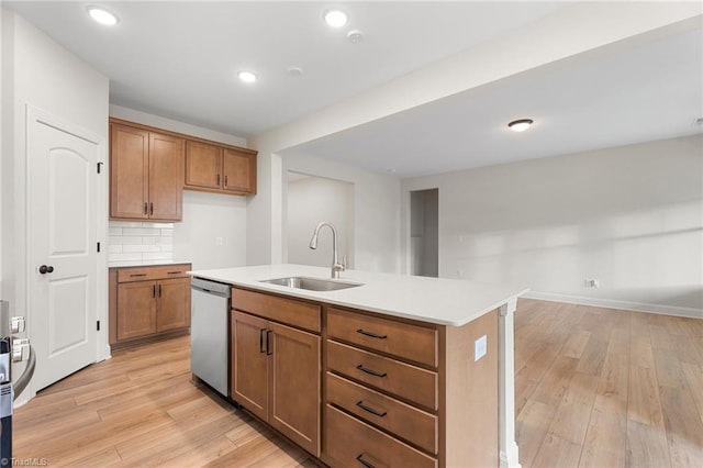 kitchen with sink, decorative backsplash, stainless steel dishwasher, a center island with sink, and light hardwood / wood-style flooring