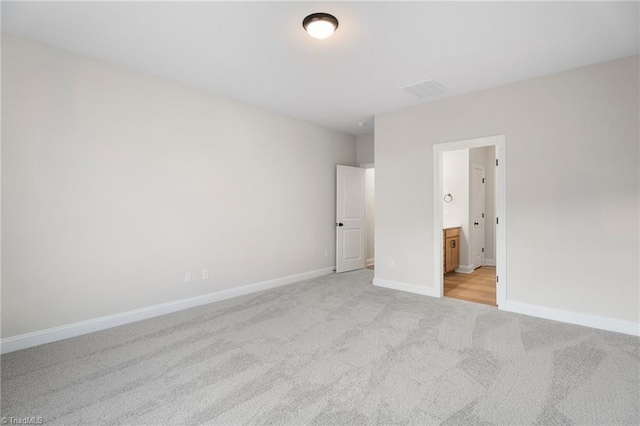 unfurnished bedroom with connected bathroom and light carpet