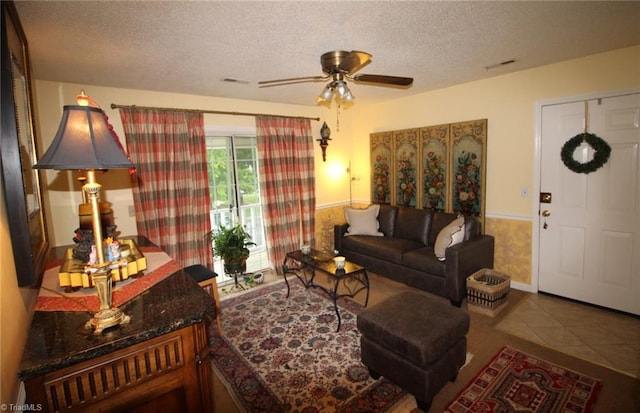 living room with tile flooring, ceiling fan, and a textured ceiling