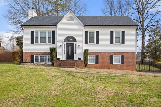 raised ranch featuring a front yard, fence, brick siding, and a chimney