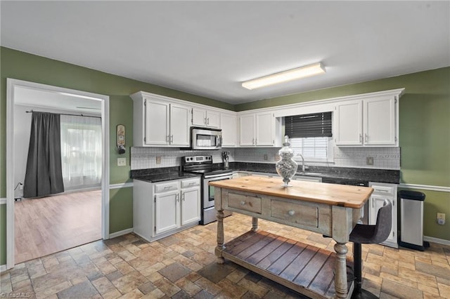 kitchen featuring stone tile flooring, white cabinetry, and stainless steel appliances