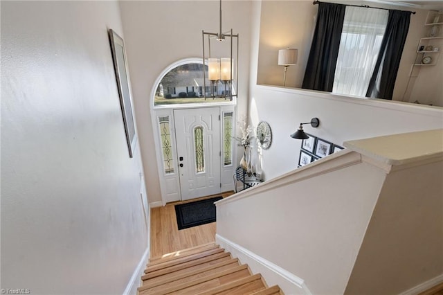 foyer entrance with baseboards, a healthy amount of sunlight, wood finished floors, and stairs