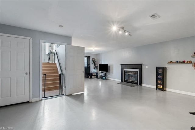 unfurnished living room with visible vents, a premium fireplace, baseboards, concrete flooring, and stairs