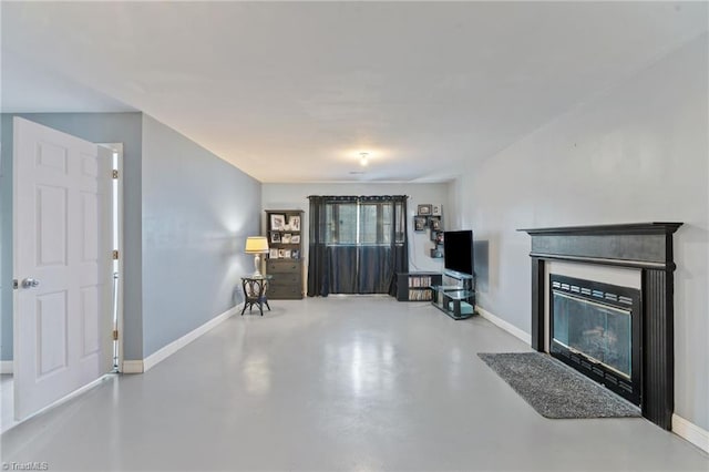 unfurnished living room featuring a glass covered fireplace, finished concrete flooring, and baseboards