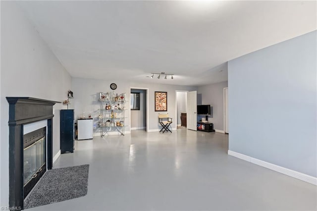 unfurnished living room featuring a glass covered fireplace, finished concrete flooring, and baseboards