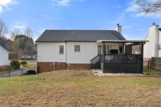 rear view of property featuring a chimney, a lawn, a wooden deck, and fence