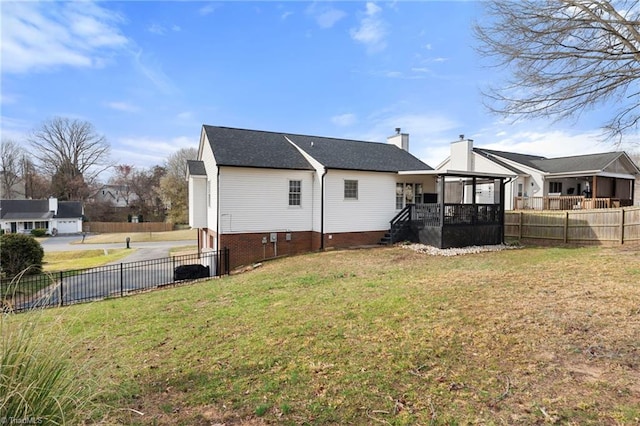 rear view of house with a lawn, a chimney, and fence