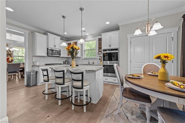 8018 Hacker Dr, Stokesdale, NC 27327 - kitchen with a chandelier, stainless steel appliances, light wood-style flooring, white cabinets, and crown molding
