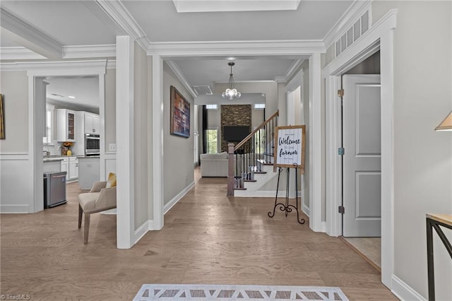 8018 Hacker Dr, Stokesdale, NC 27327 - foyer entrance featuring a chandelier, light wood finished floors, ornamental molding, stairs, and baseboards