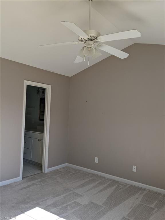 empty room featuring lofted ceiling, light carpet, a ceiling fan, and baseboards