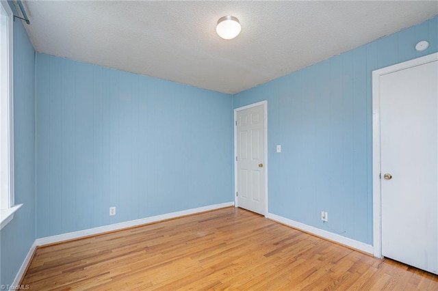 spare room featuring light hardwood / wood-style floors and a textured ceiling