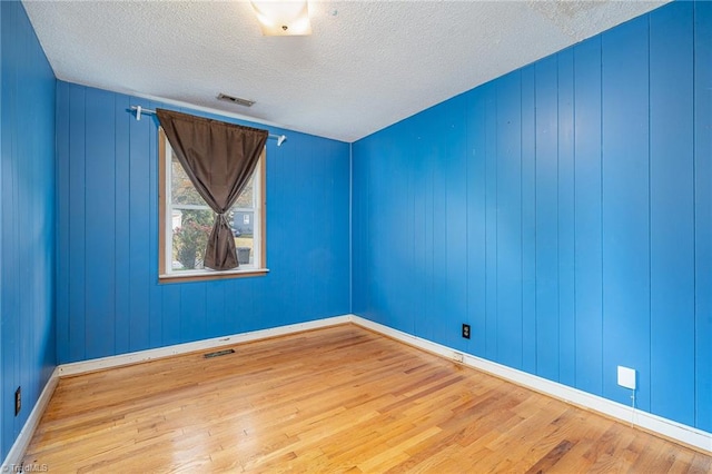 empty room featuring wood-type flooring and a textured ceiling