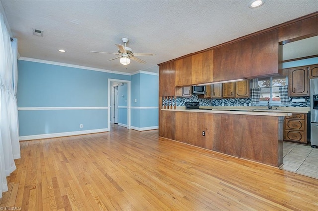 kitchen with crown molding, ceiling fan, tasteful backsplash, light hardwood / wood-style floors, and kitchen peninsula