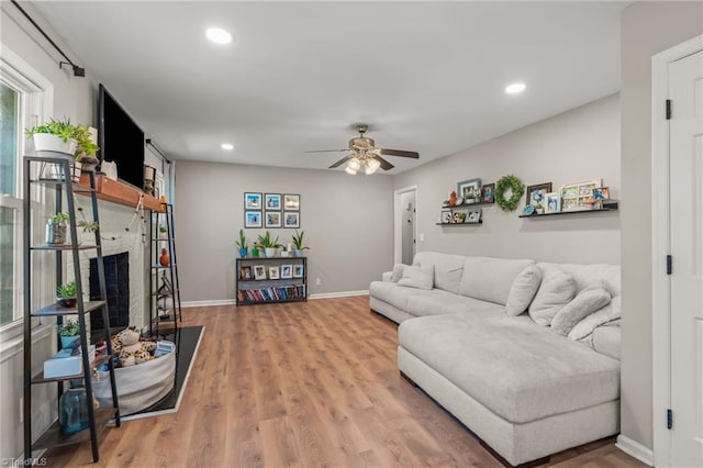 living room featuring hardwood / wood-style flooring, a fireplace, and ceiling fan