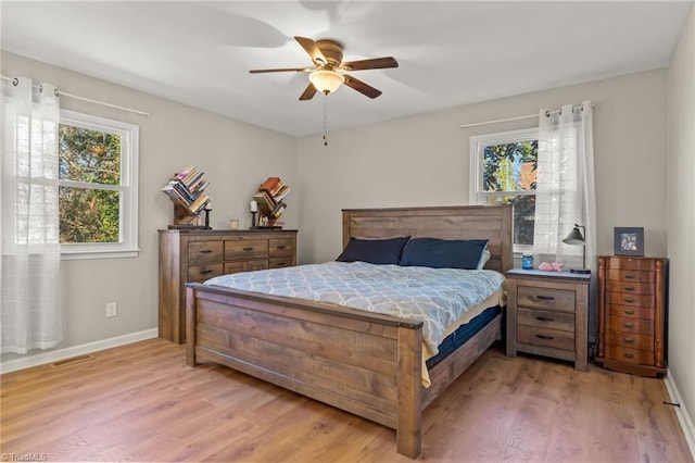 bedroom featuring ceiling fan, multiple windows, and light wood-type flooring