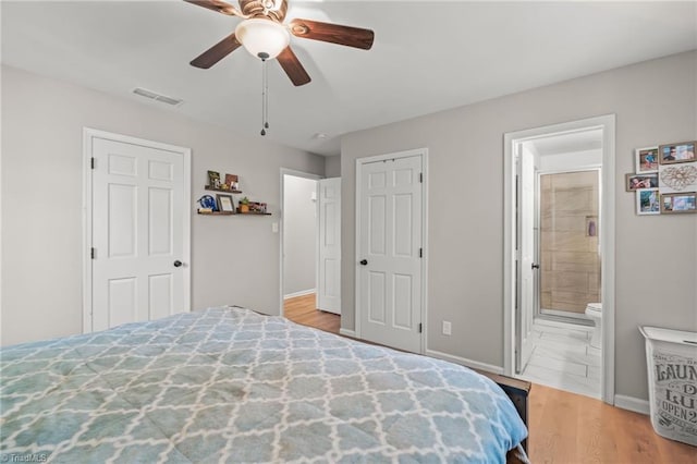 bedroom with ceiling fan, ensuite bath, and light wood-type flooring