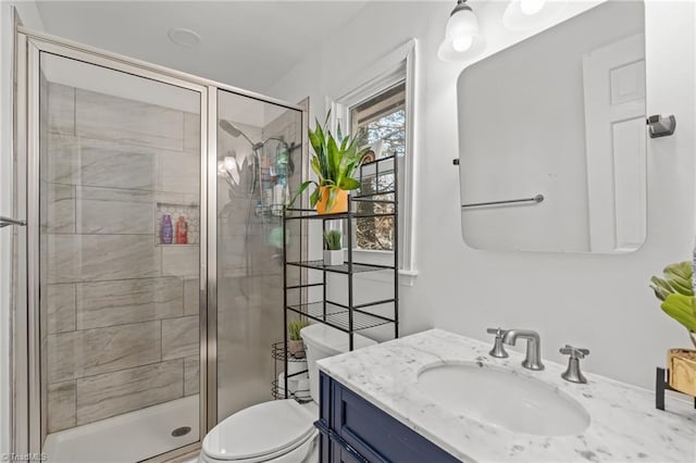 bathroom with walk in shower, vanity, and toilet