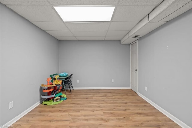 playroom with a paneled ceiling and light wood-type flooring